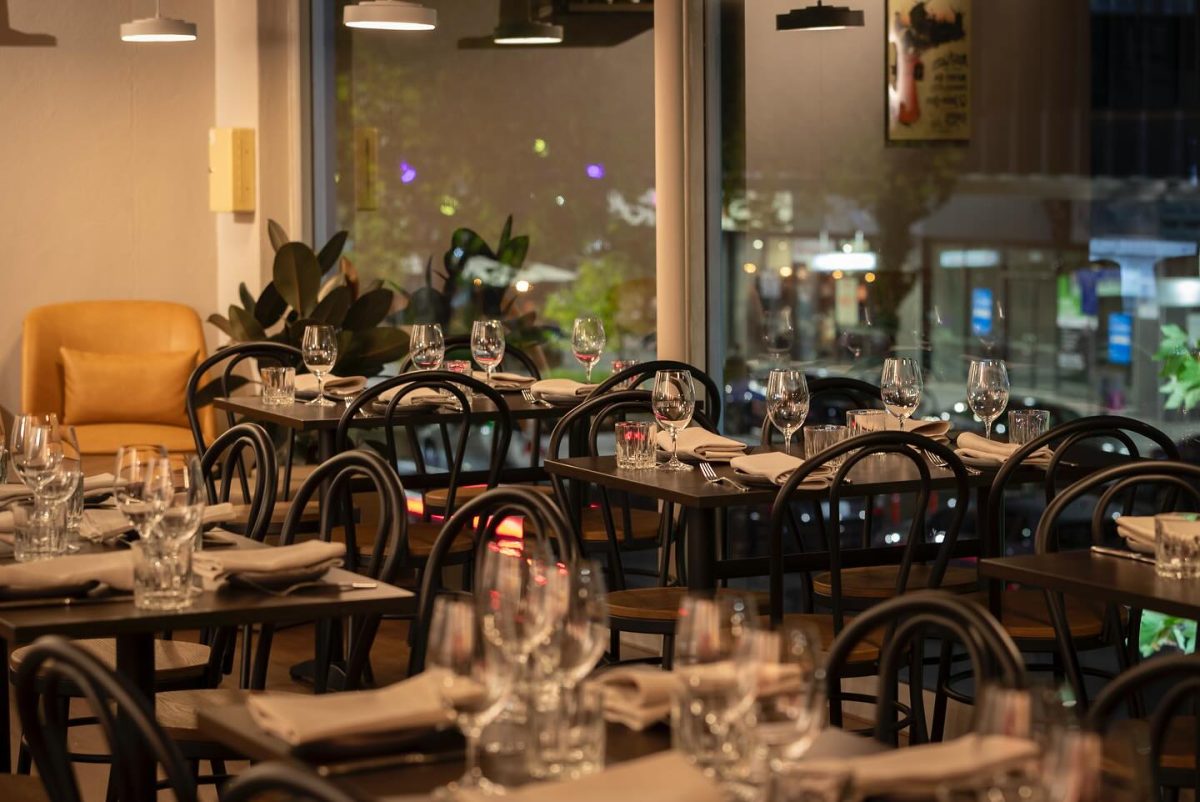 Interior of restaurant with large windows looking out onto dark streetscape.
