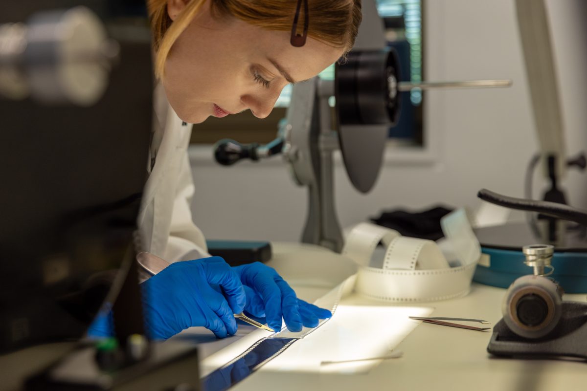 A woman bending over to restore analogue material