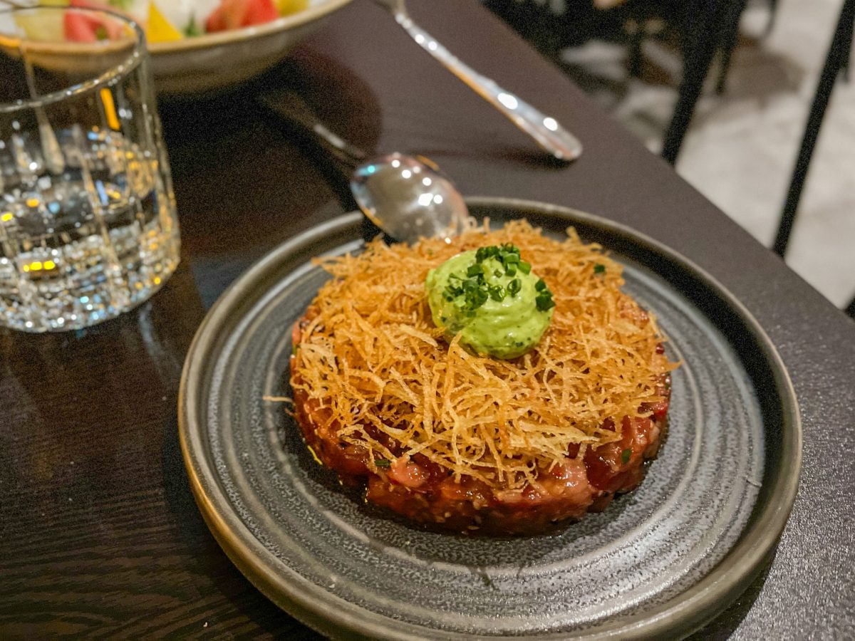 Tuna tartare covered in a layer of crispy grated potato with a green garnish.
