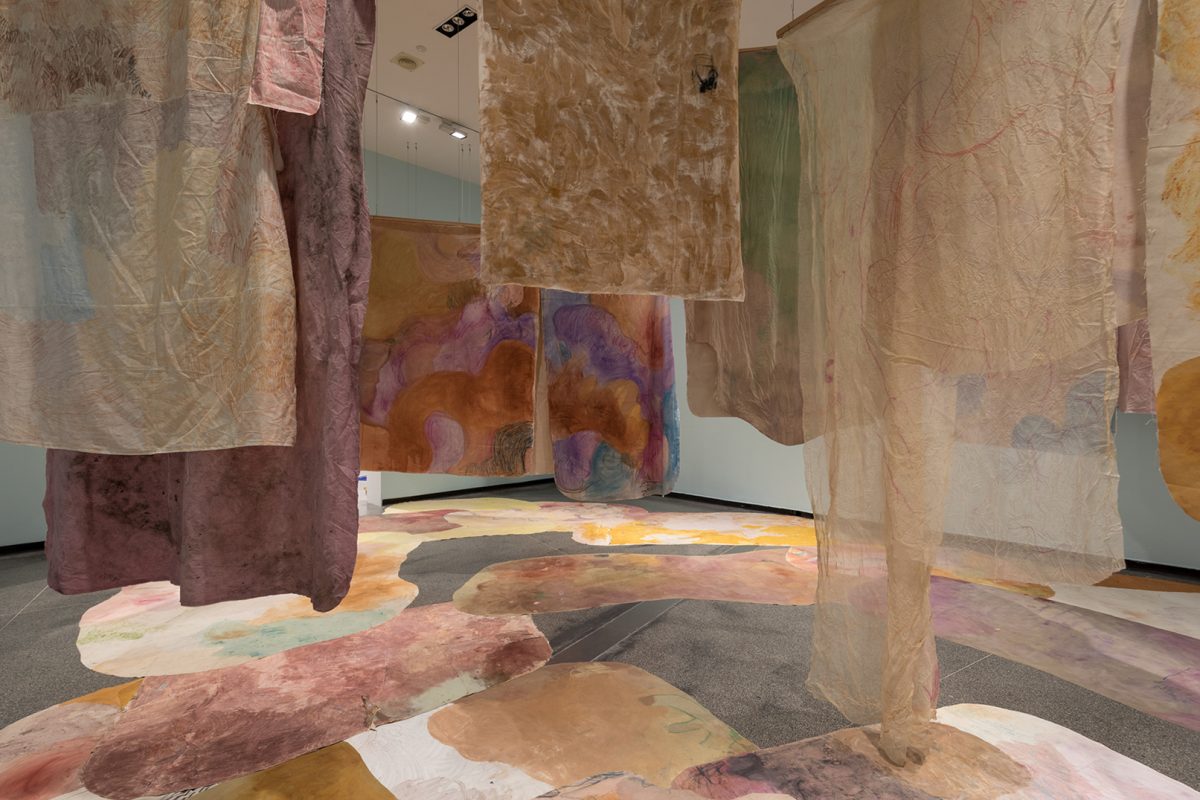 Numerous hanging painted sheets from the ceiling
