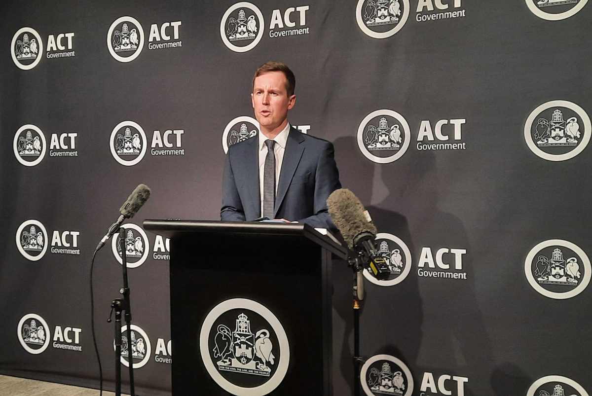 man speaking at a lectern during a press conference