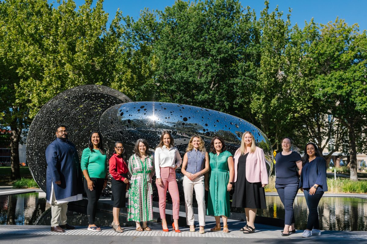 A man and several women in front of Canberra artwork