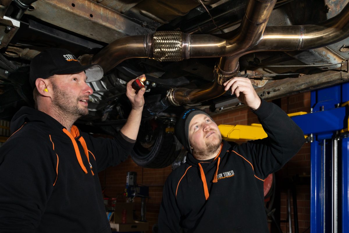 Two mechanics looking underneath a car