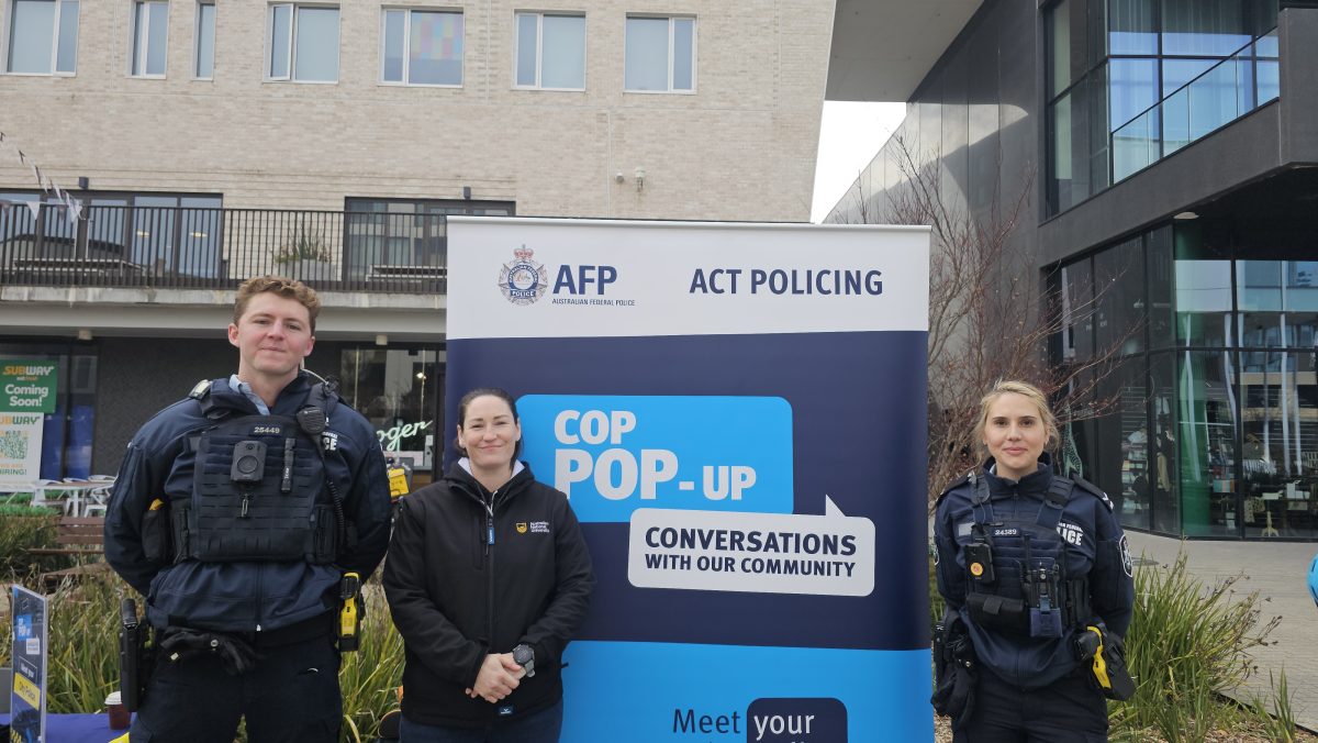 Two police officers and an ANU security manager in front of a Cop Pop-Up sign on campus