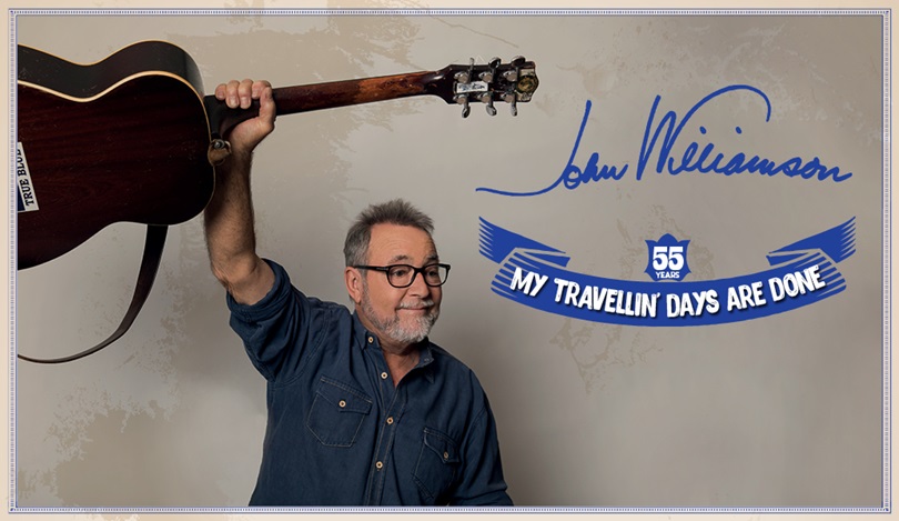 John Williamson holding a guitar in the air