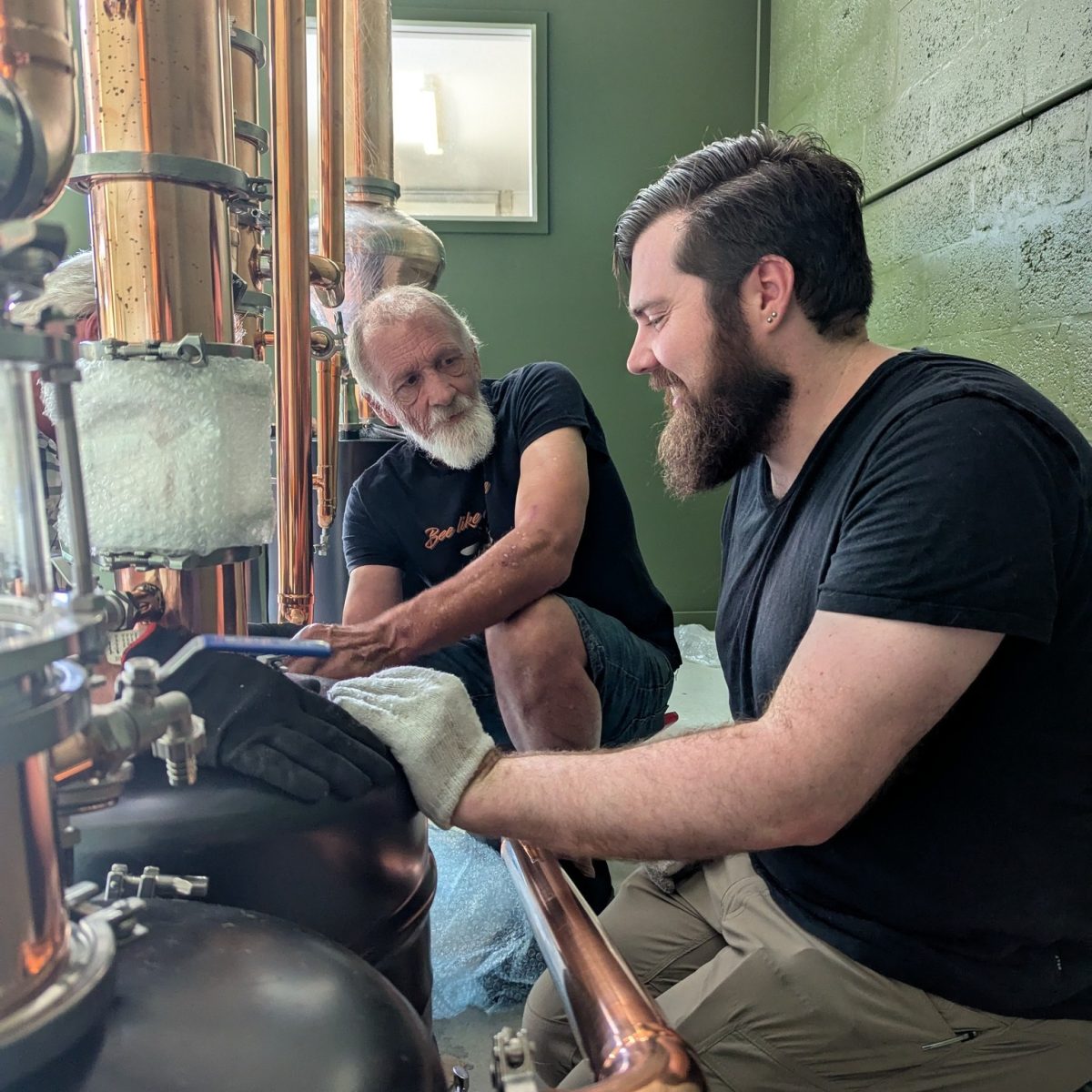 An older man and younger man working on a still together.