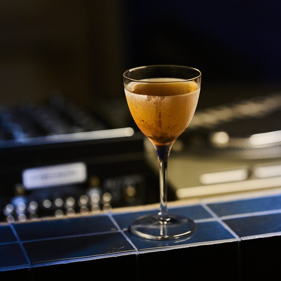 A cocktail sitting on blue tiles.