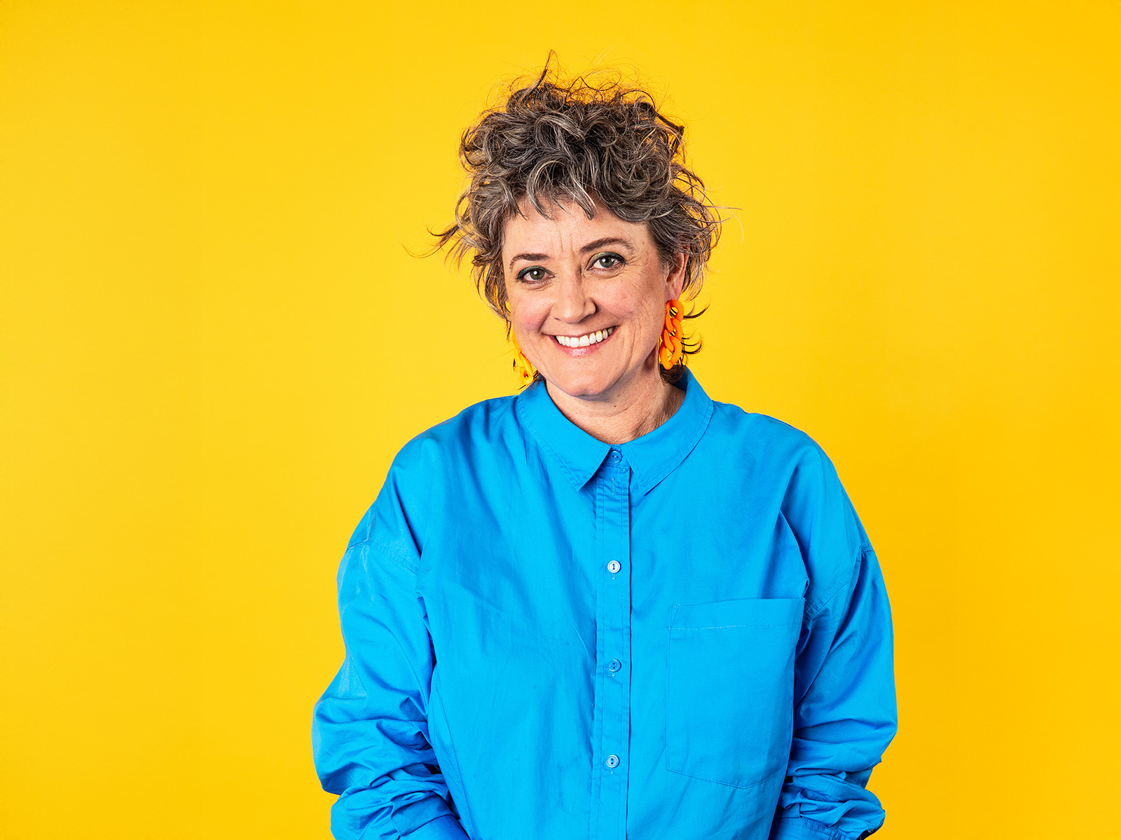 Chris Ryan wearing a blue shirt standing in front of a yellow background