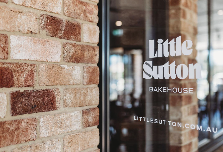 The entrance doorway of Little Sutton Bakery, featuring it's logo on the door.