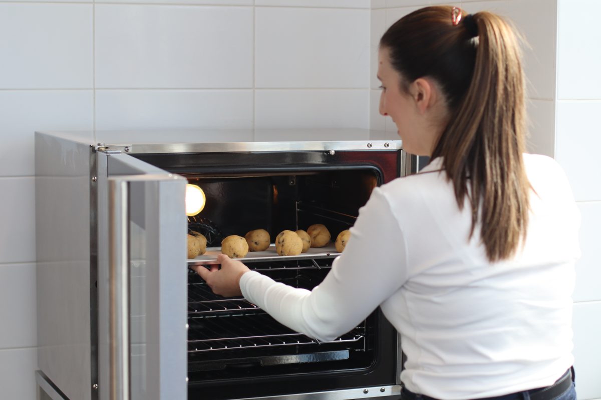 Woman puts cookie dough into oven.