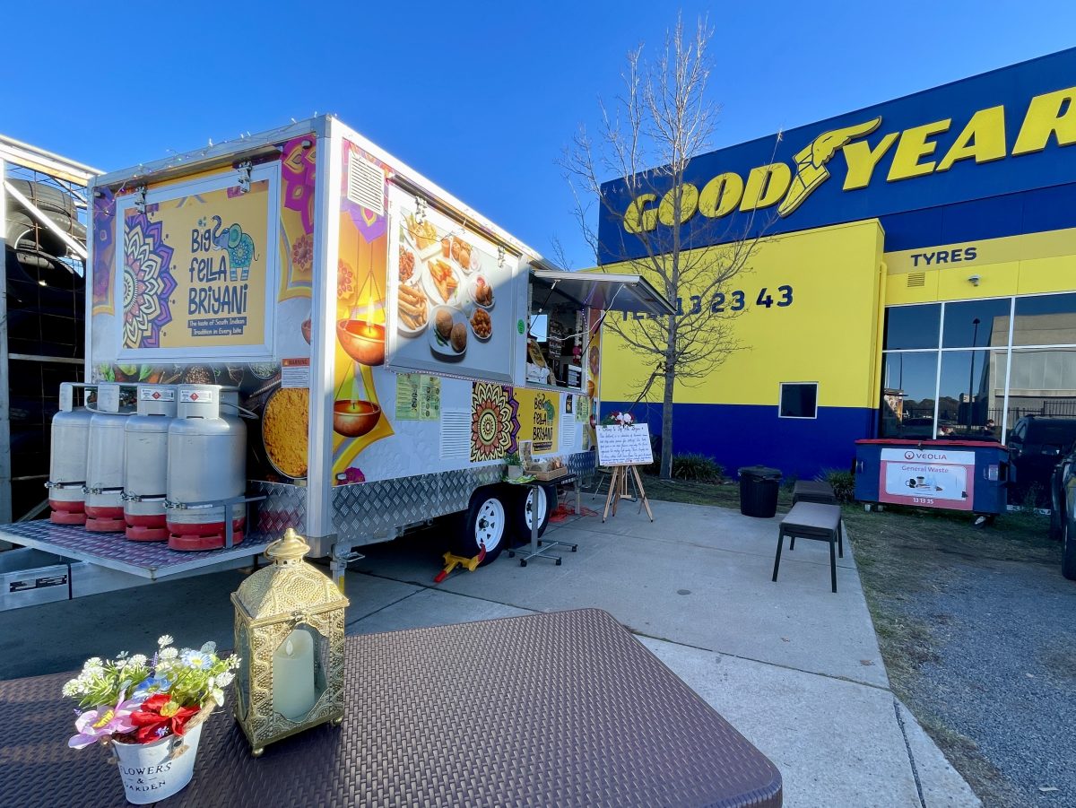 A colourful food truck parked in front of a Good Year Tyre store.