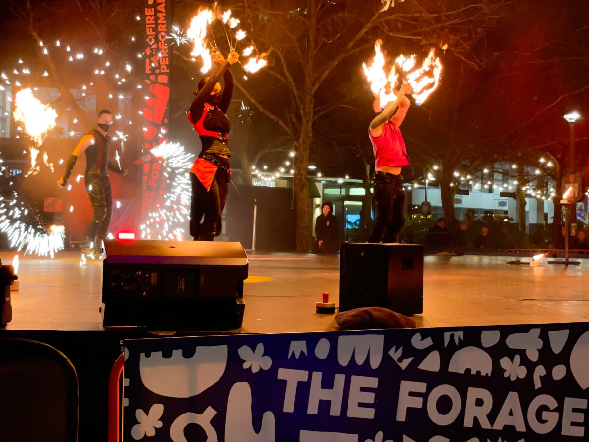 Performers dance with fire on stage.