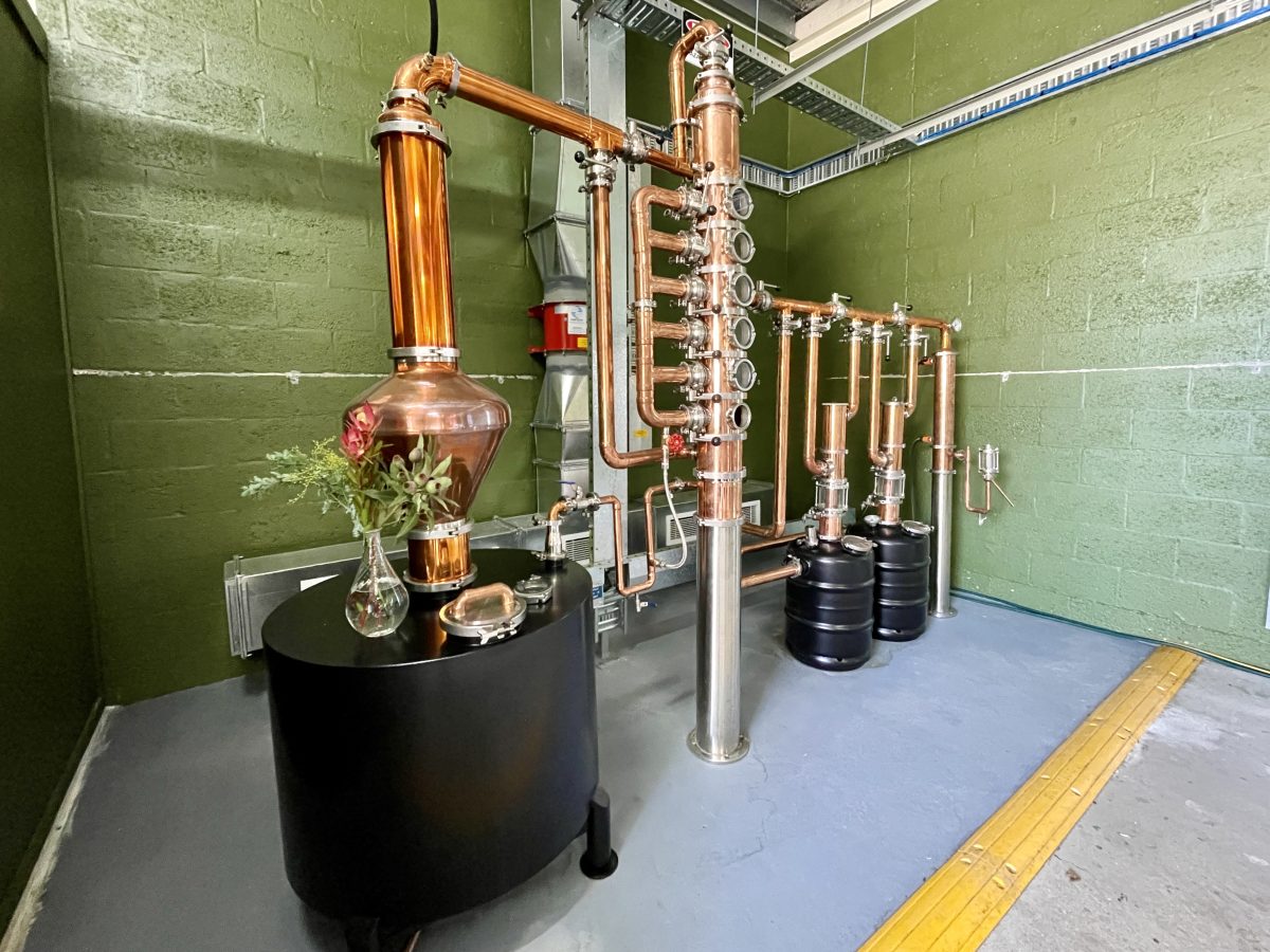 A copper still against a green wall. 