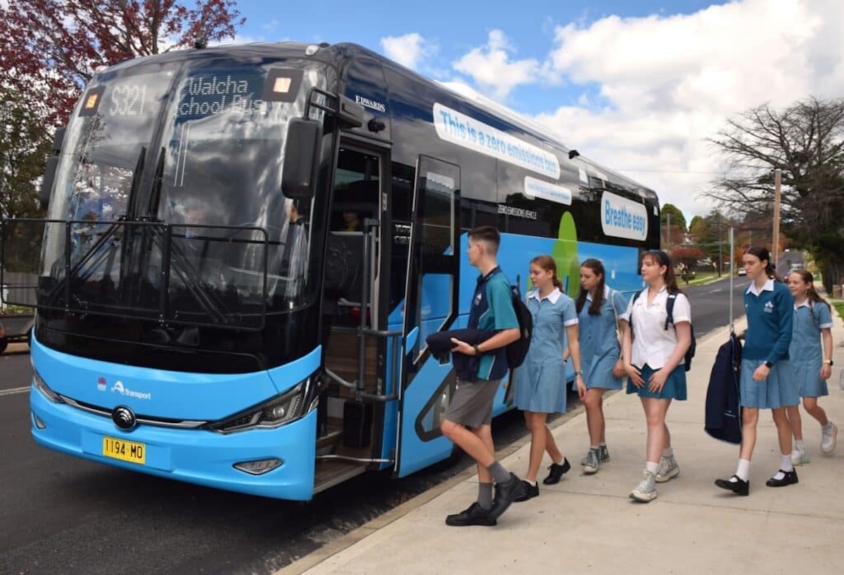 School students board an electric bus.