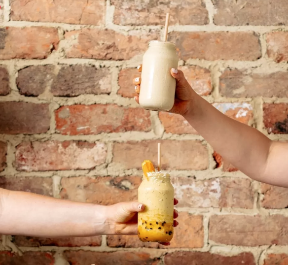 Two arms hold out different flavours of smoothie