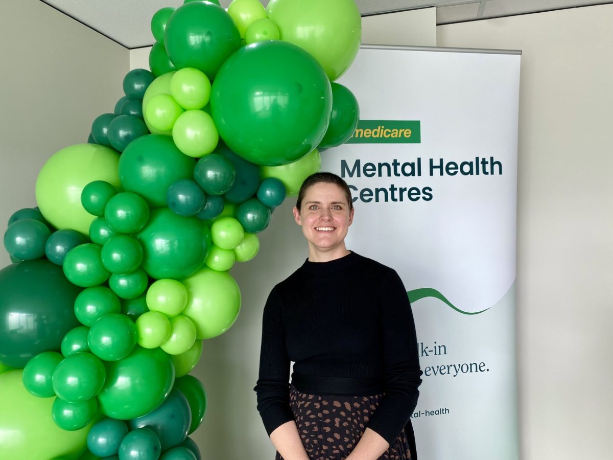 Stacy Leavens standing in front of mental health centre poster