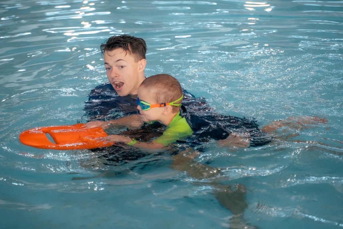 a swimming instructor in a pool with a child holding a kickboard