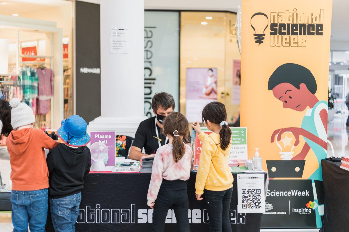 a group of people standing at a science stall in a shopping centre