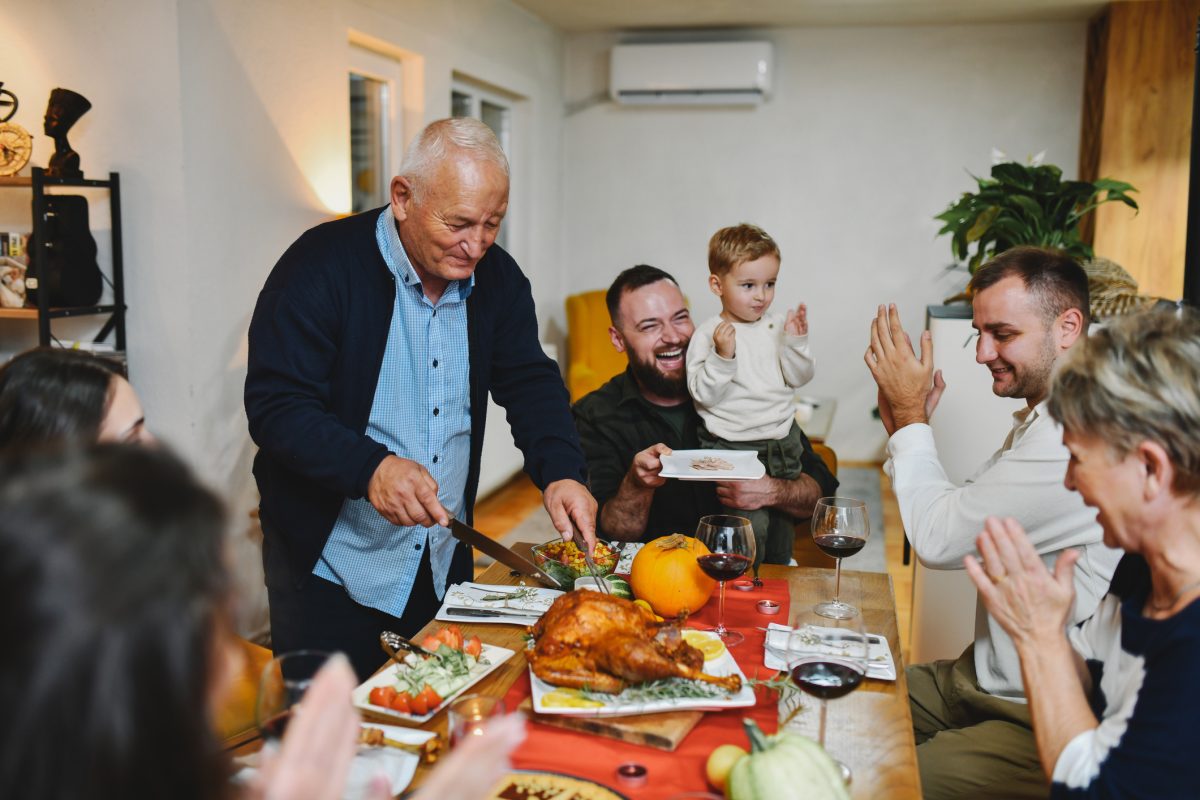 Happy Family Waiting for Piece of Turkey While Grandpa is Cutting and Sharing