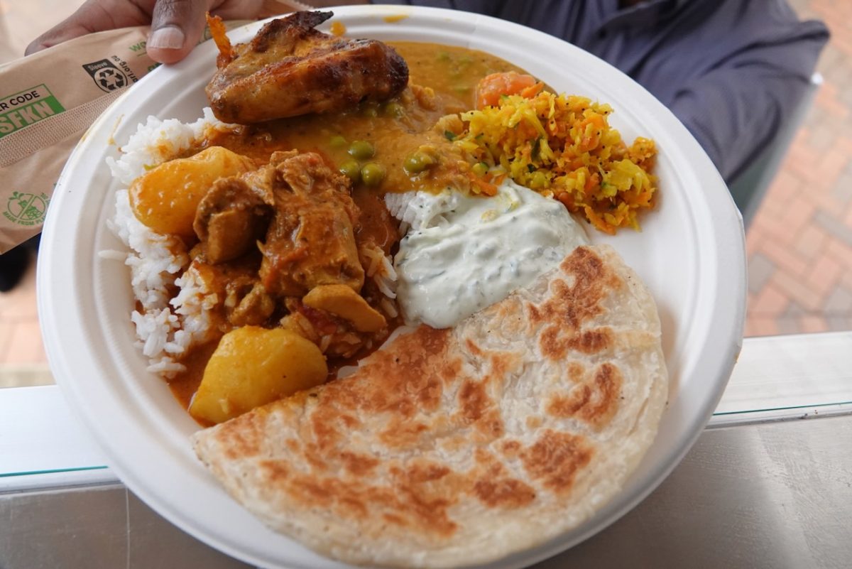 A plate with roti bread, curry, rice and raita.
