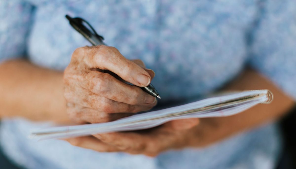 senior woman's hands writing in notebook