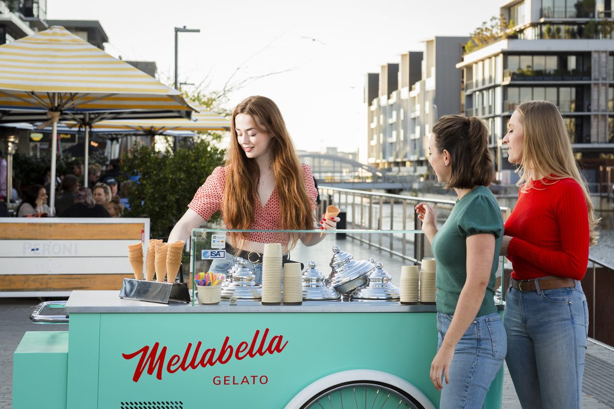 Woman scoops gelato for two customers.