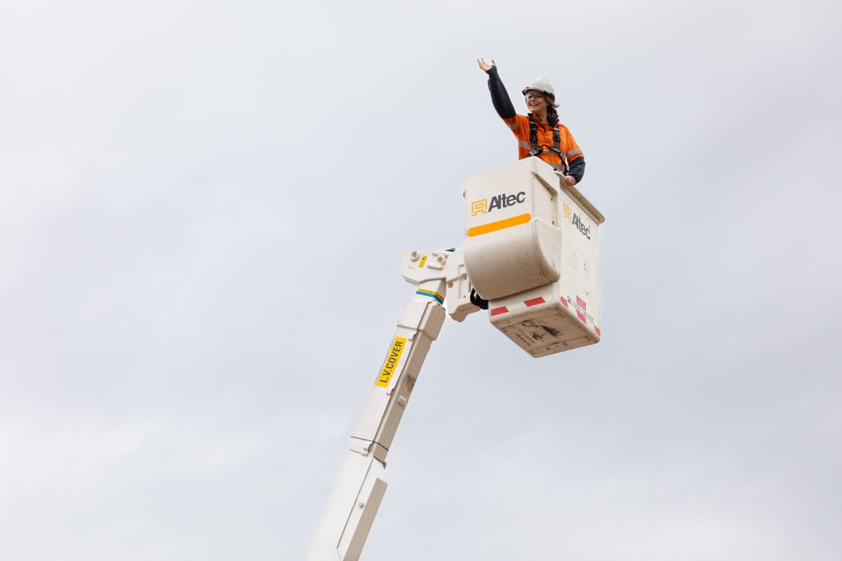 Evoenergy worker waves from atop a crane