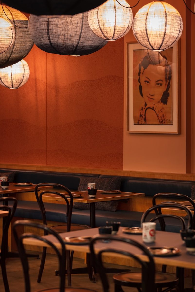 Interior of restaurant with lantern lights and a retro looking print of a woman on the wall.