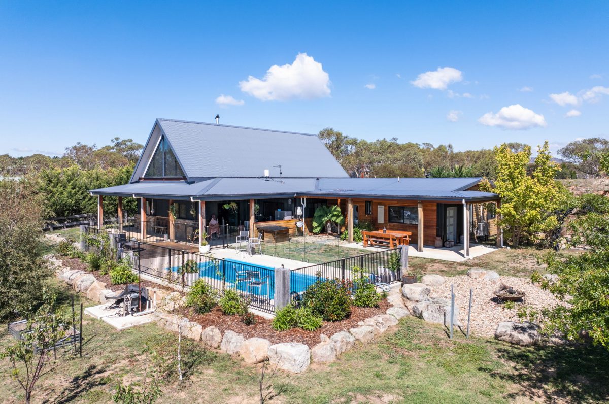 elevated view of stylish home with inground pool and established gardens