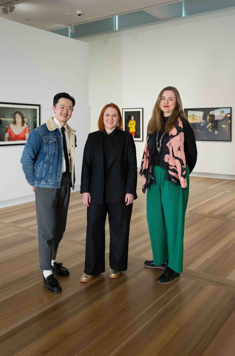 Three people standing in an art gallery