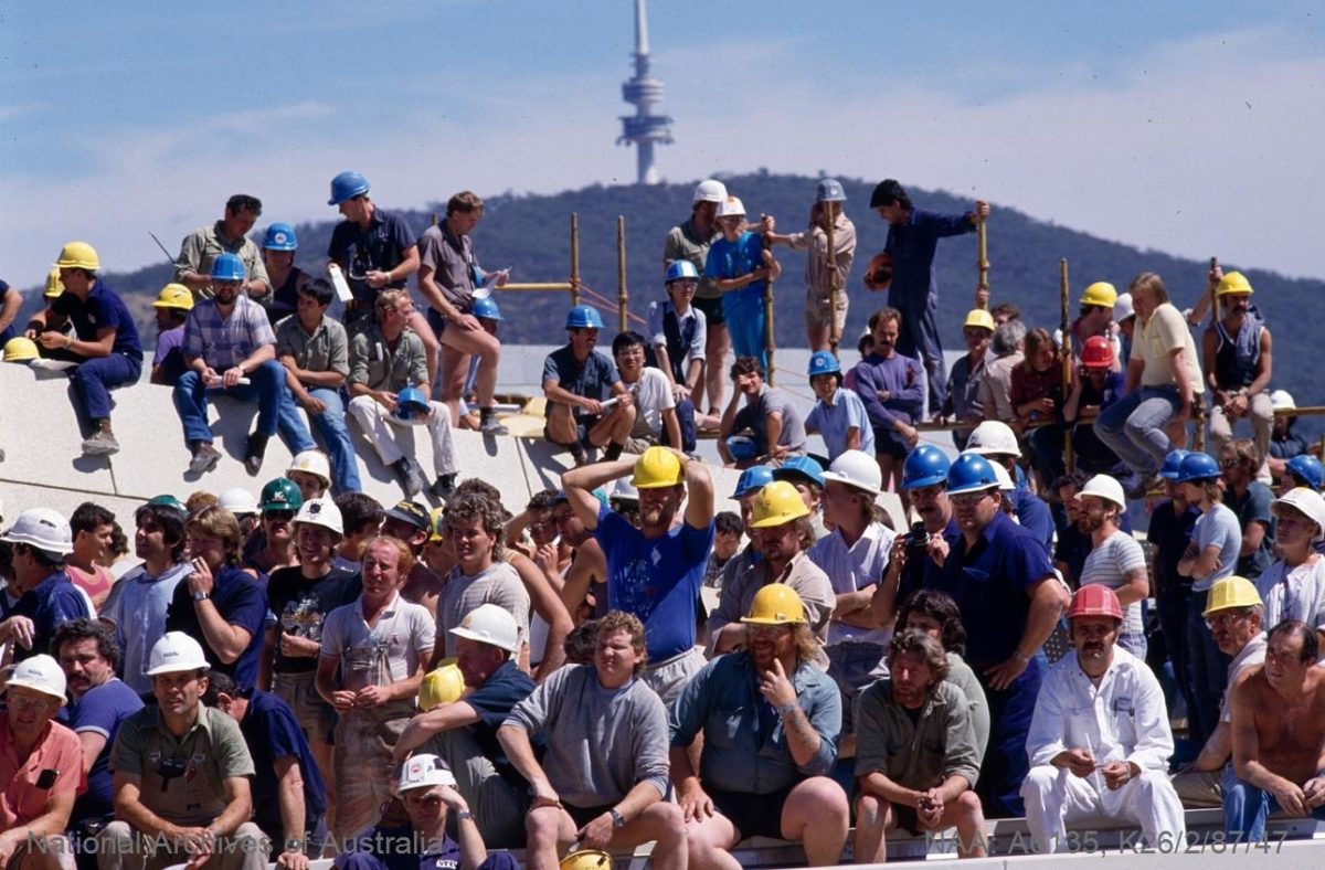 A group of construction workers gather for a posed photo with Telstra Tower in the background