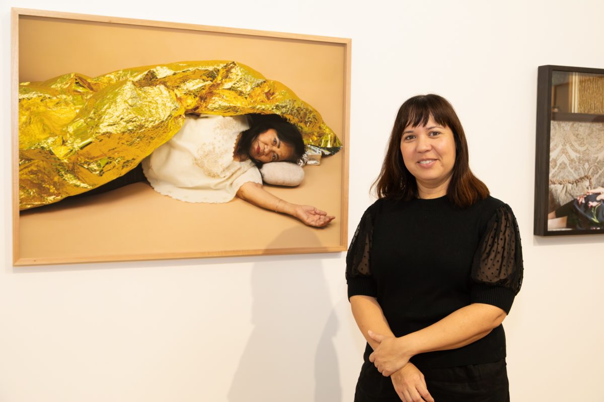 Woman standing next to a photograph displayed on a wall