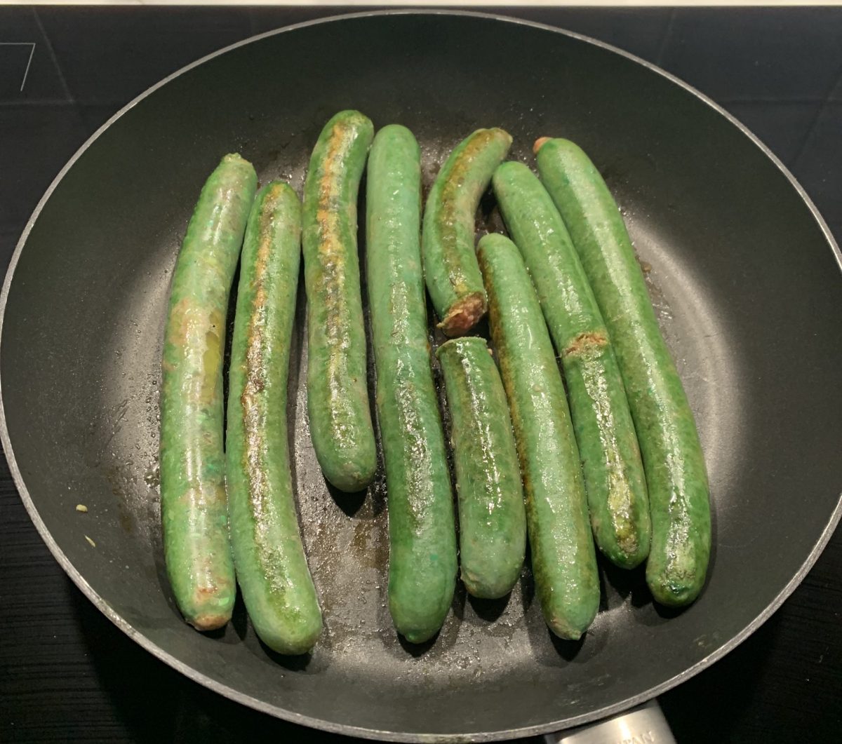 green sausages in a frypan