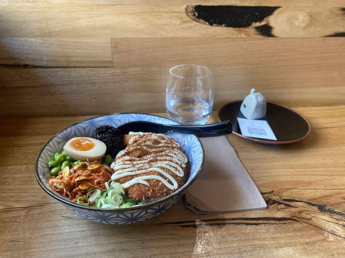 A bowl with fried chicken, mayo, an egg and veggies. 