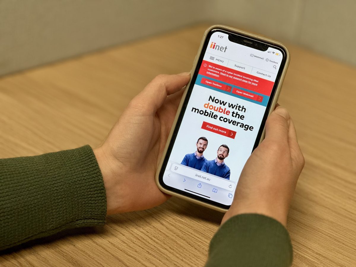 person holding phone with iiNet home screen