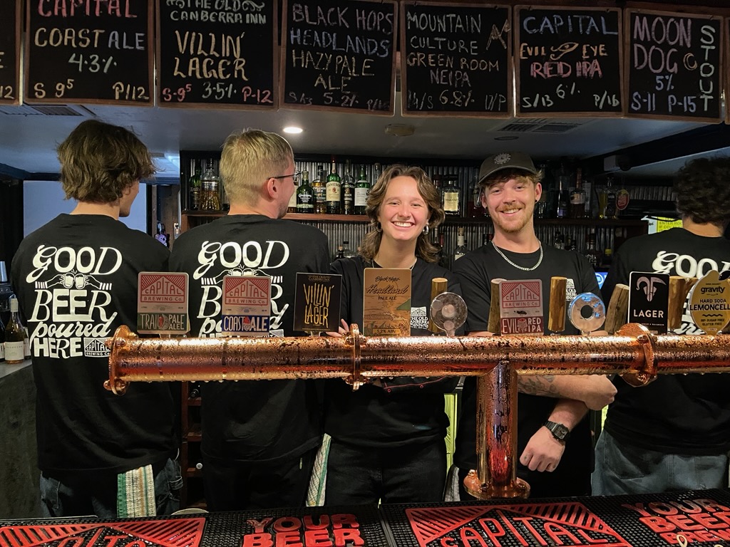 Four bartenders behind a bar.