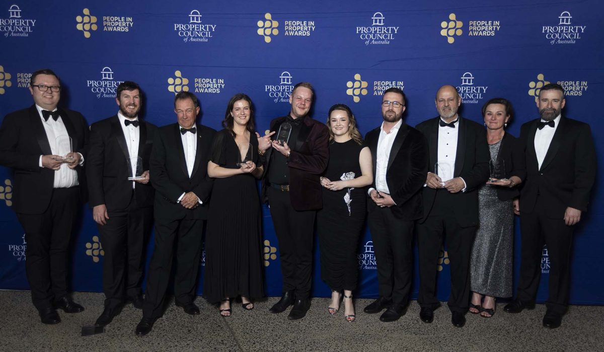 A group of people standing in front of a media wall holding awards