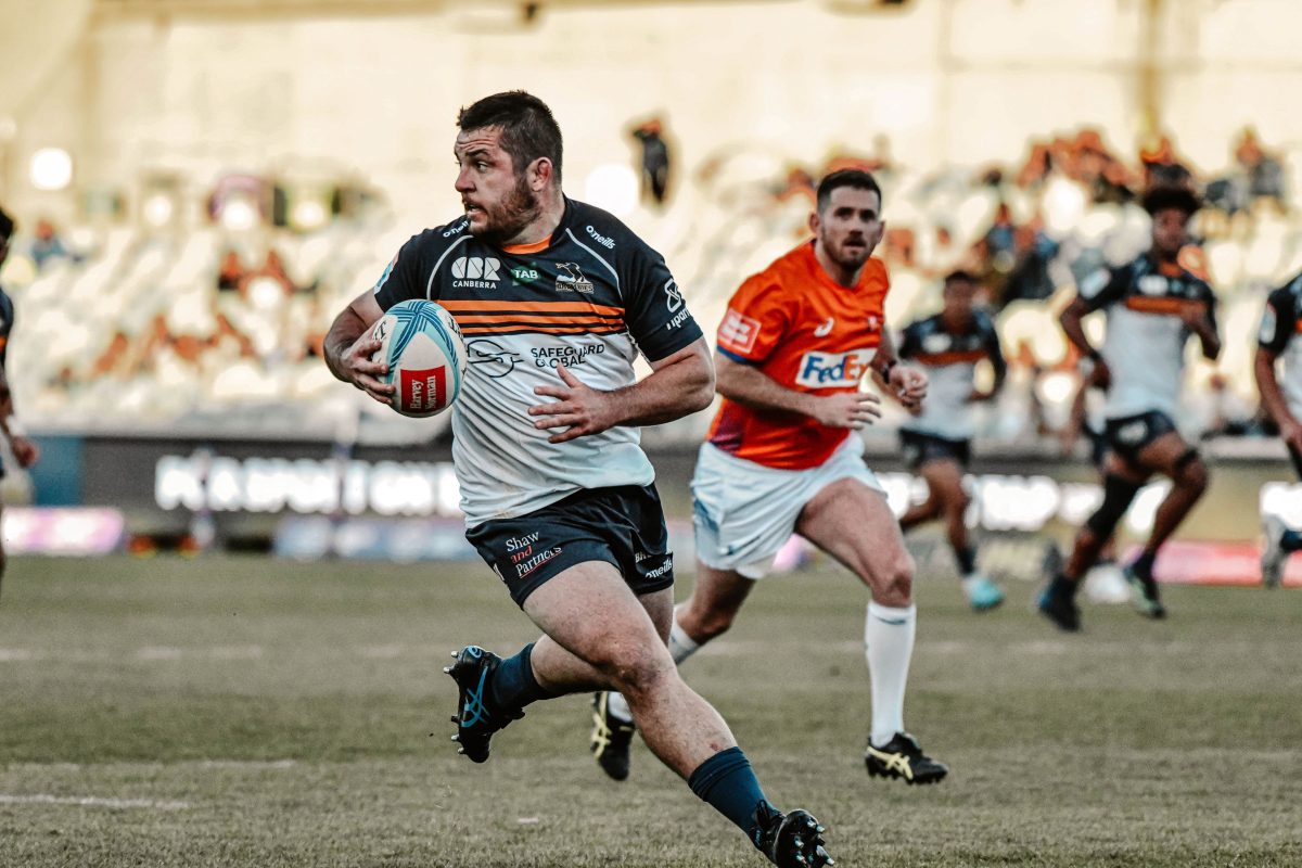 Connal McInerney carries the ball on the rugby field