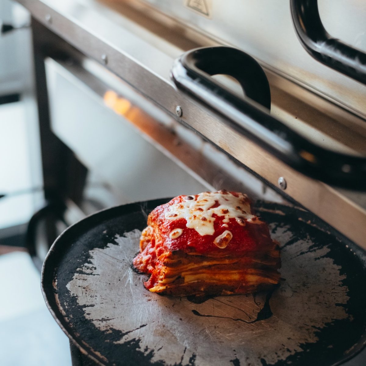 A square of lasagna on a round baking tray.
