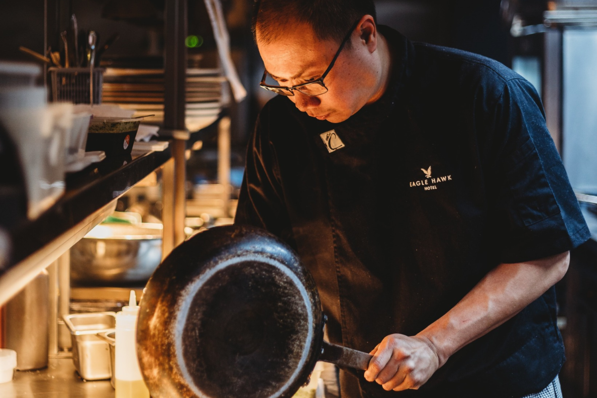 Chef holding pan in commercial kitchen.