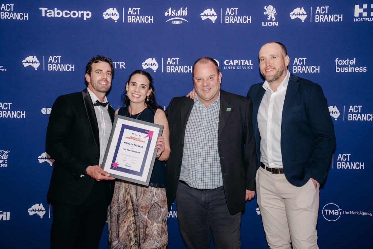 A group photo of four people holding a framed certificate.