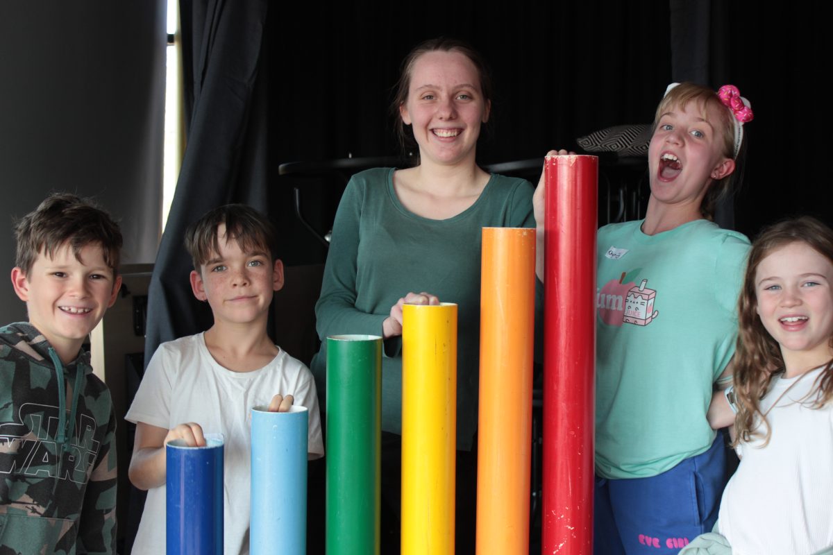 a group of 5 people standing next to rainbow coloured poles