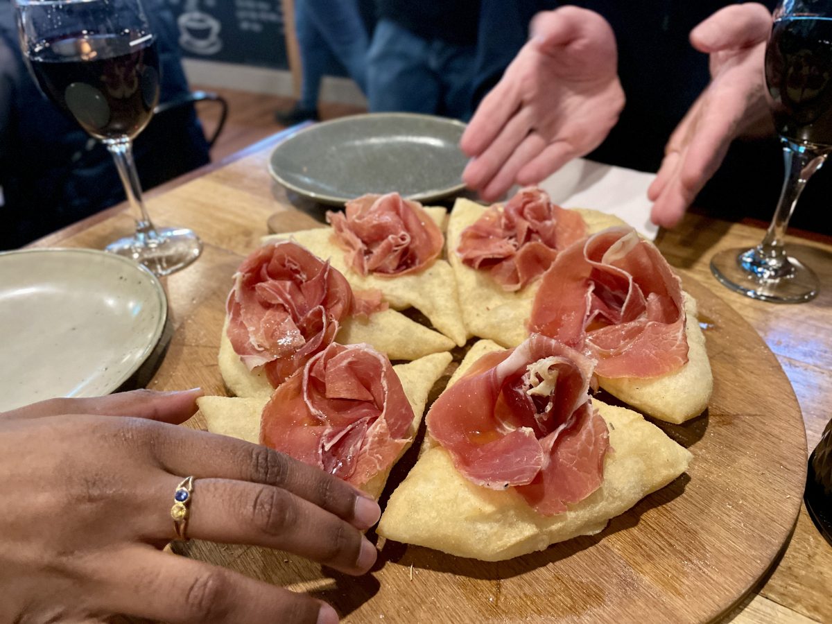 A wheel of triangles of fried dough topped with rosettes of cured ham.