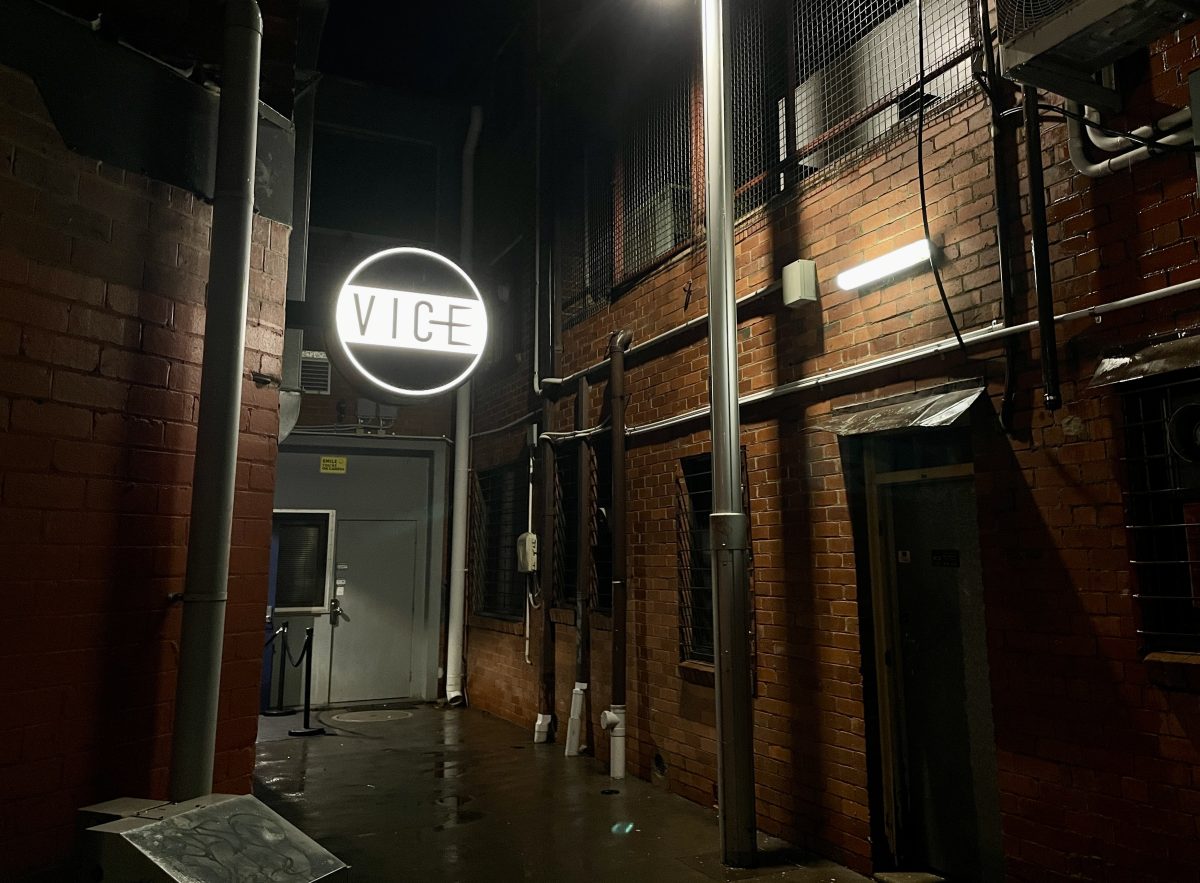 An alleyway with lit-up circular sign reading VICE.