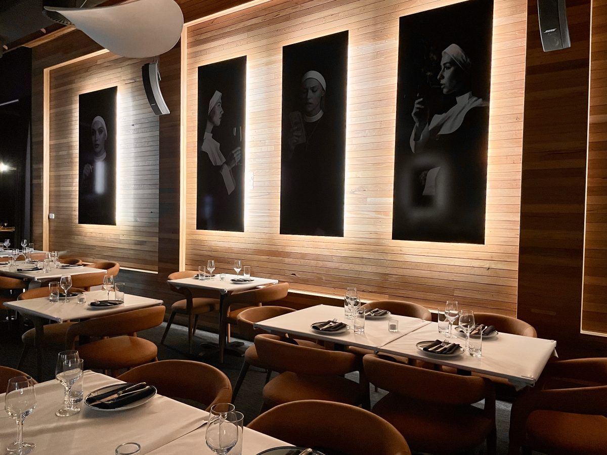 Dark black and white portraits of models dressed as nuns in a restaurant.
