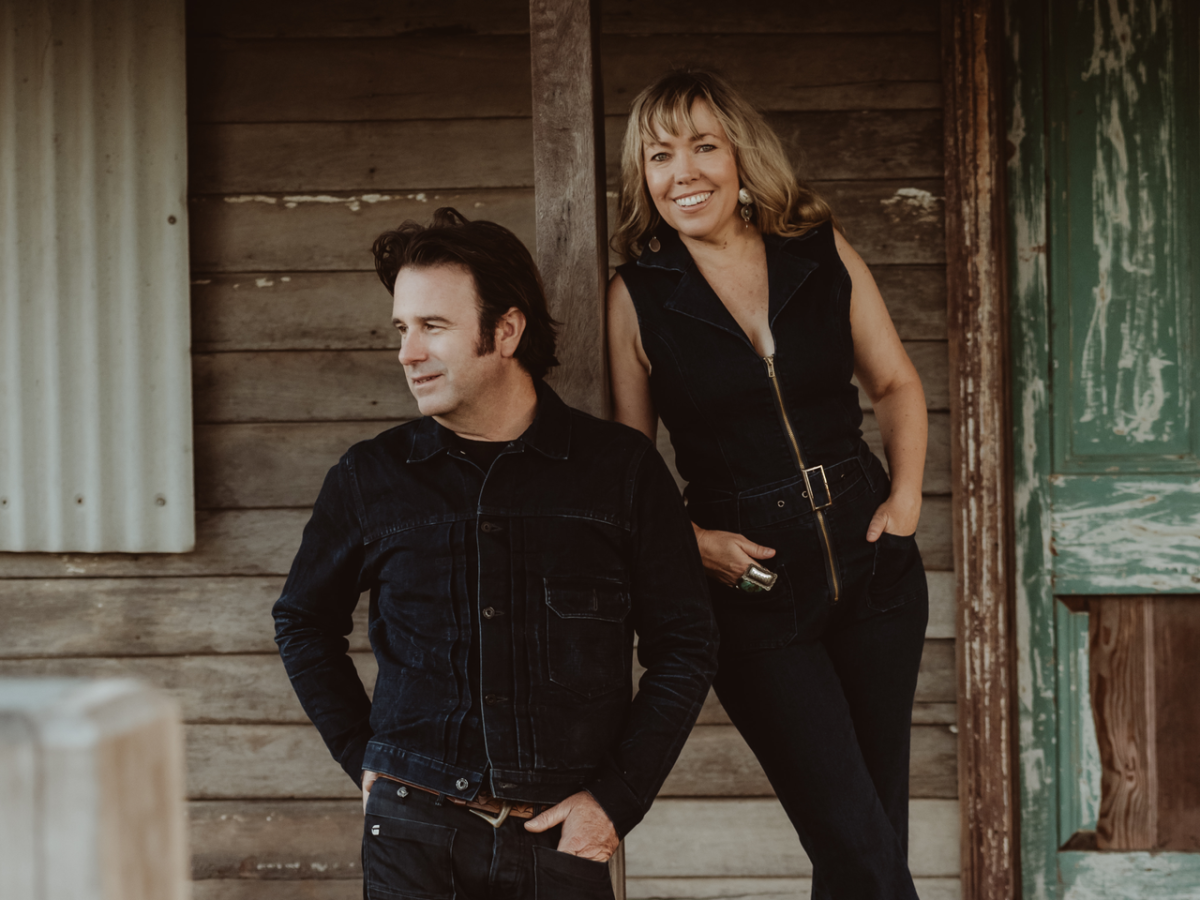 a man and a woman standing at an old timber building