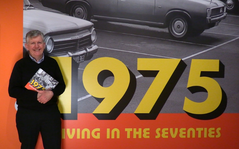 Guy Hansen holding the 1975 exhibition book in a gallery