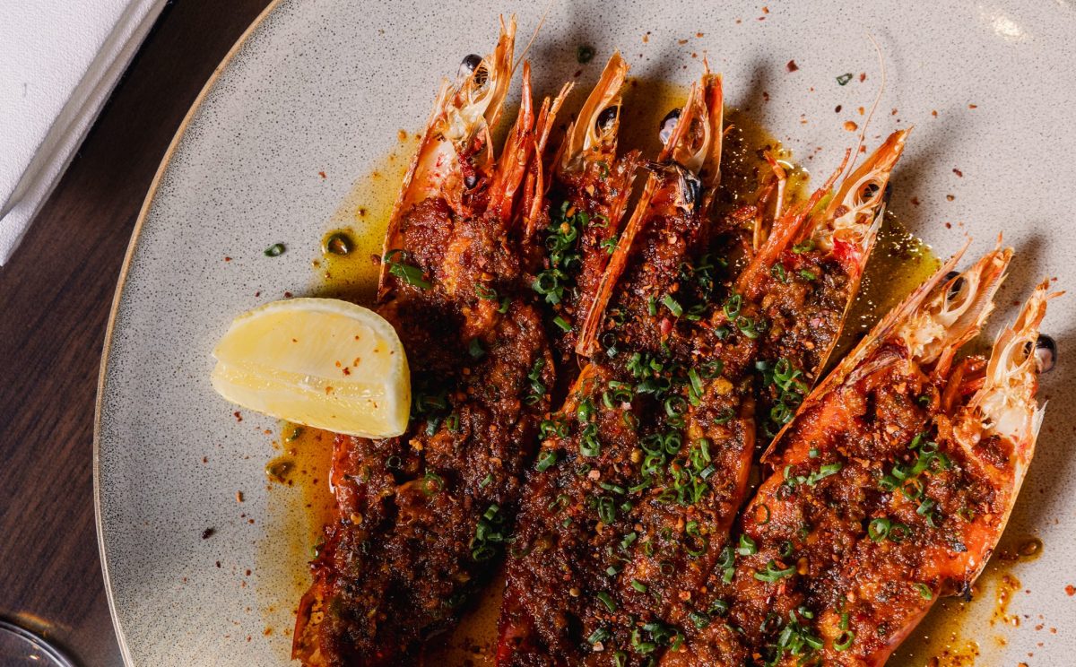 a close up of a plate of cooked prawns with a wedge of lemon