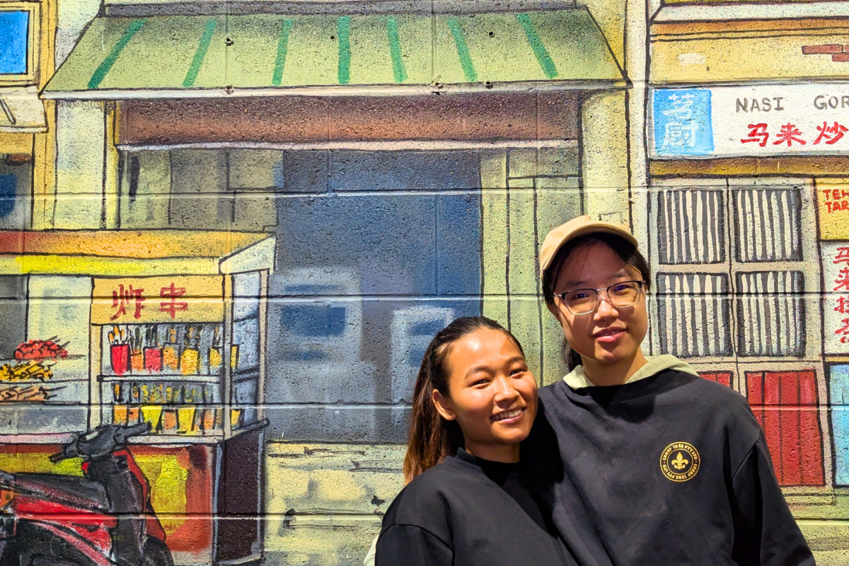 Two women in from of Malaysian street mural.