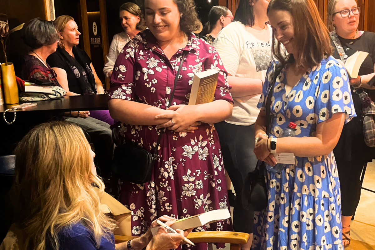 Woman signs books at author talk.
